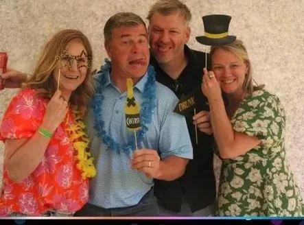 Four concert guests in leis and hats at the Pic Booth booth at the Jackson-Triggs Summer Concert Series