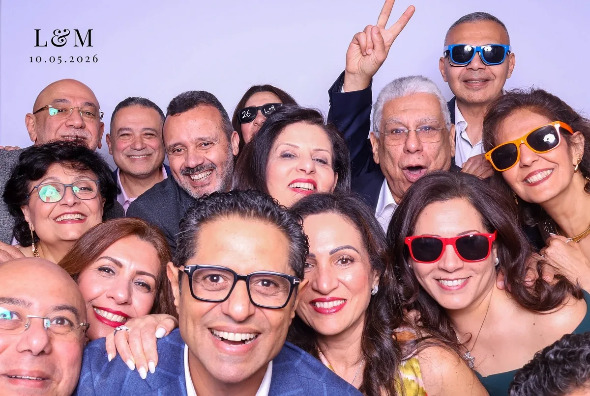 A crowd of engagement party guests in party sunglasses packed into one monogrammed Magic Mirror print