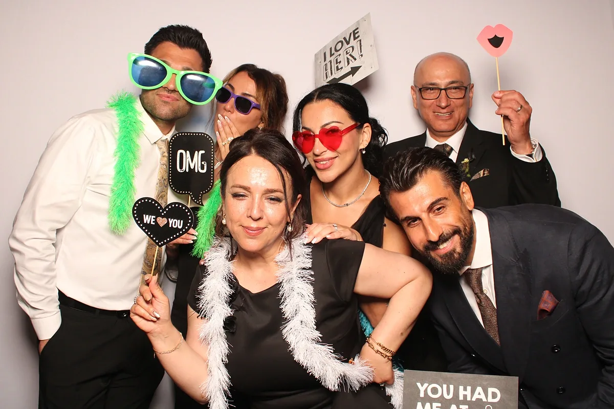 Reception guests in feather boas holding heart and OMG signs at the Calamus Magic Mirror