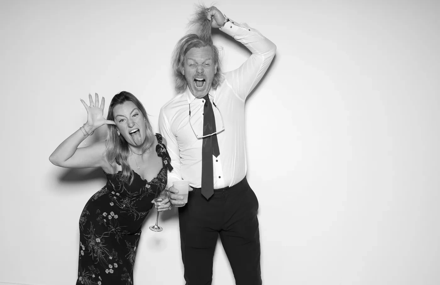 A couple pulling faces in a high-contrast black and white glam photo booth print