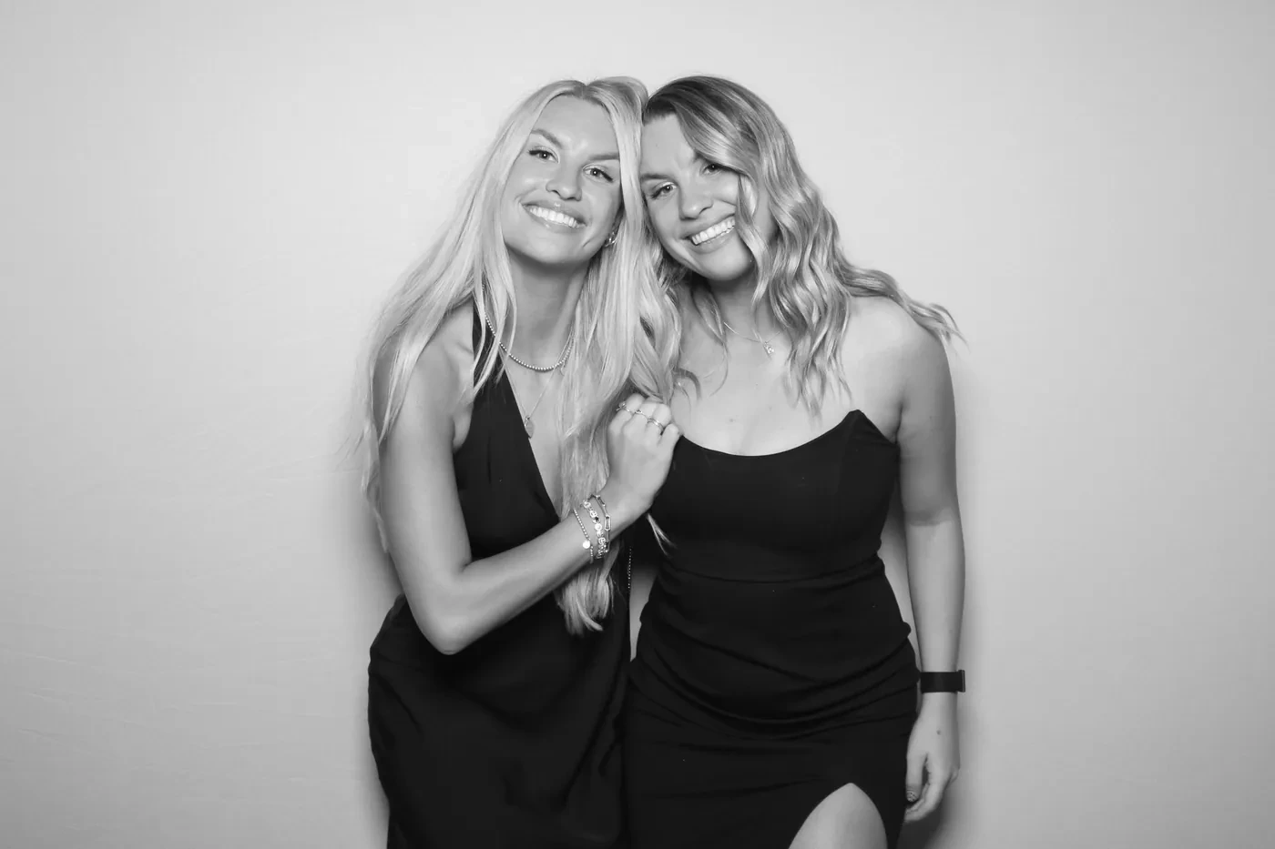 Two friends in black and white at a Pic Booth glam photo booth, studio-lit against a plain backdrop
